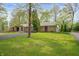 Charming single-story home with stone facade, a large green lawn, and a paved driveway at 8245 Woodlawn Dr, Martinsville, IN 46151