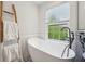 Bright bathroom featuring a soaking tub, window, and a decorative wood ladder at 877 Rosalind Pl, Carmel, IN 46032
