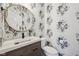 Stylish powder room with a round mirror, unique floral wallpaper, and a modern vanity at 877 Rosalind Pl, Carmel, IN 46032