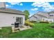 Backyard featuring green lawn, gray patio, grill, and manicured bushes under cloudy skies at 9713 Springcress Dr, Noblesville, IN 46060