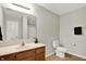 Bathroom with a laminate floor, wood vanity and a toilet and shower with door visible in the mirror at 9713 Springcress Dr, Noblesville, IN 46060
