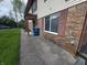 An exterior view of the apartments brick facade with red shutters and a cement pathway and grassy lawn at 10063 Penrith Dr, Indianapolis, IN 46229