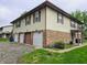 Exterior view of a two-story building with beige siding, brick facade, and attached garages at 10063 Penrith Dr, Indianapolis, IN 46229