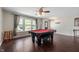 Well-lit living room with dark hardwood floors, billiard table, and large windows with curtain accents at 10625 Gathering Dr, Indianapolis, IN 46259