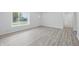 A bedroom with newly installed gray vinyl floors, white walls and trim, and a window with natural light at 1116 Heatherwood Dr, Indianapolis, IN 46241