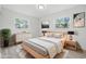 A staged bedroom with neutral decor, two windows, and light wood flooring at 1116 Heatherwood Dr, Indianapolis, IN 46241
