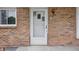Close up of a brick front porch with a white front door with a storm door and exterior lights at 1116 Heatherwood Dr, Indianapolis, IN 46241