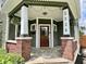 Inviting front porch with brick columns, string lights, and a wood door at 1328 Sturm Ave, Indianapolis, IN 46202