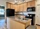 Kitchen boasting a central island, stainless steel sink, black appliances, and wooden cabinetry at 1328 Sturm Ave, Indianapolis, IN 46202