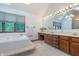 Bright bathroom featuring a tub, skylight, large vanity and mirrors at 1421 Stoney Creek Cir, Carmel, IN 46032