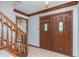 Inviting entryway with double doors featuring glass inserts, wood trim, tiled floor, and wooden staircase at 1421 Stoney Creek Cir, Carmel, IN 46032