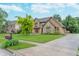 Well-kept home with a stone and siding exterior, complemented by a green lawn, mature trees, and a paved driveway at 1421 Stoney Creek Cir, Carmel, IN 46032