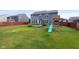 Spacious backyard with green lawn, play set, and privacy fence offers outdoor fun at 14584 Hinton Dr, Fishers, IN 46037