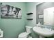 Cozy powder room with a pedestal sink, modern fixtures, stylish decor, and black shelving against a fresh, light green wall at 14584 Hinton Dr, Fishers, IN 46037