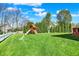 Large backyard with lush green grass, a wooden playset, and privacy trees at 14817 Deerwood Dr, Carmel, IN 46033