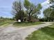 The exterior view of a rustic single-story home, surrounded by mature trees, with a long driveway at 1598 Commerce Way, Pittsboro, IN 46167