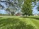 Exterior shot of a single-story home with mature trees, large grassy yard, and long driveway at 1598 Commerce Way, Pittsboro, IN 46167