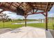 Pergola with fans on concrete patio overlooking pond, fountain, and green grass at 17023 Adler Ln, Noblesville, IN 46060