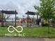 Community playground with a black metal fence, swingset, and mature landscaping at 1710 S Birch St, Muncie, IN 47302