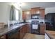 Kitchen featuring a window, wood cabinetry, black appliances and tile floors at 1739 Elderberry Dr, Indianapolis, IN 46234