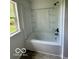 White bathtub with shower with built-in shelves, and a bright window offering natural light at 1945 Plantation Ln, Martinsville, IN 46151