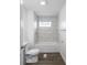 A white bathroom features a tiled shower over the tub, toilet, and vinyl floor at 204 N Vine St, Shelbyville, IN 46176