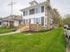 Side view of a two-story gray home with a stone chimney, featuring a well-kept lawn and landscaped front yard at 204 N Vine St, Shelbyville, IN 46176