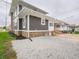 A charming home featuring a gravel driveway, well-kept lawn, and stylish exterior with gray stucco and stone accents at 204 N Vine St, Shelbyville, IN 46176