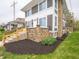 Close-up of a two-story gray home's stone siding, complemented by well-maintained landscaping and greenery at 204 N Vine St, Shelbyville, IN 46176