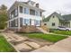 Side view of a gray two-story home, showcasing a stone foundation and a driveway with grassy front lawn at 204 N Vine St, Shelbyville, IN 46176