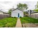 Backyard featuring a detached garage with gray siding, a blue door, and a well-maintained lawn at 2237 N New Jersey St, Indianapolis, IN 46205