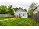 Backyard featuring a detached garage, wooden deck with picnic table, lush green grass, and fencing at 2237 N New Jersey St, Indianapolis, IN 46205