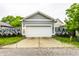View of detached garage with a white door, light gray siding, and surrounded by lush greenery at 2237 N New Jersey St, Indianapolis, IN 46205