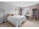 Bright bedroom featuring a bed, a desk with shelving, and gray and pink striped accent wall at 2396 Creek Bank Dr, Columbus, IN 47201
