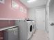 Convenient laundry room with washer, dryer, storage shelves and pink accent wall at 2396 Creek Bank Dr, Columbus, IN 47201