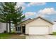 Charming single-story home featuring neutral siding, a two-car garage, and a well-manicured front lawn with a large tree at 2449 Orchard Creek Dr, Columbus, IN 47201