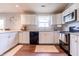 Modern kitchen with white cabinetry, dark appliances, light countertops, and dark laminate floors with a window view at 2449 Orchard Creek Dr, Columbus, IN 47201