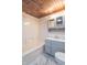 Bathroom showcasing bathtub and shower with marble flooring, complemented by wooden ceiling and ample vanity storage at 2539 S Lyons Ave, Indianapolis, IN 46241
