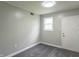 Bright room featuring neutral walls, carpet flooring, a window, and a door at 2539 S Lyons Ave, Indianapolis, IN 46241