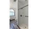 A bathroom with a glass enclosed shower, black fixtures, laminate floors, and an arched window at 2985 Little Hurricane Rd, Martinsville, IN 46151