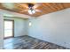 An angled view of a bedroom with an exterior door and octagon window, wood paneled walls, and vinyl flooring at 2985 Little Hurricane Rd, Martinsville, IN 46151