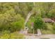 Aerial view showing a home's spacious yard, mature trees, a pond, a firepit, an outbuilding, and gravel parking areas at 4091 W Briarwood Lake S Dr, Monrovia, IN 46157