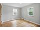 A neutral bedroom with hardwood floors, two windows, and a door to the side at 4730 Rookwood Ave, Indianapolis, IN 46208