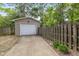View of the detached single car garage with concrete driveway and fenced yard with mature trees at 5526 Indianola Ave, Indianapolis, IN 46220