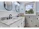 Bright bathroom featuring double sinks, a marble countertop, black fixtures, and a window bringing in natural light at 6288 Buttonwood Dr, Noblesville, IN 46062