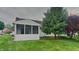 Back exterior view of house with a screened-in porch, mature trees, and well-maintained lawn at 7018 Mallard Way, Plainfield, IN 46168