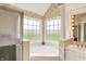Bright bathroom featuring a soaking tub surrounded by windows, floral wallpaper and a tile floor at 7110 Koldyke Dr, Fishers, IN 46038