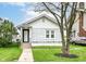 Charming home featuring a white-painted brick exterior, well-manicured lawn, and sidewalk leading to the front door at 736 N Dequincy St, Indianapolis, IN 46201
