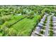 Overhead shot reveals a broad green field, edged by verdant trees, houses, and a pond, illustrating a blend of residential and rural charm at 7425 E Thompson Rd, Indianapolis, IN 46239