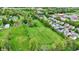 Aerial view highlighting a lush green field alongside houses and a pond, with a school visible in the background at 7425 E Thompson Rd, Indianapolis, IN 46239